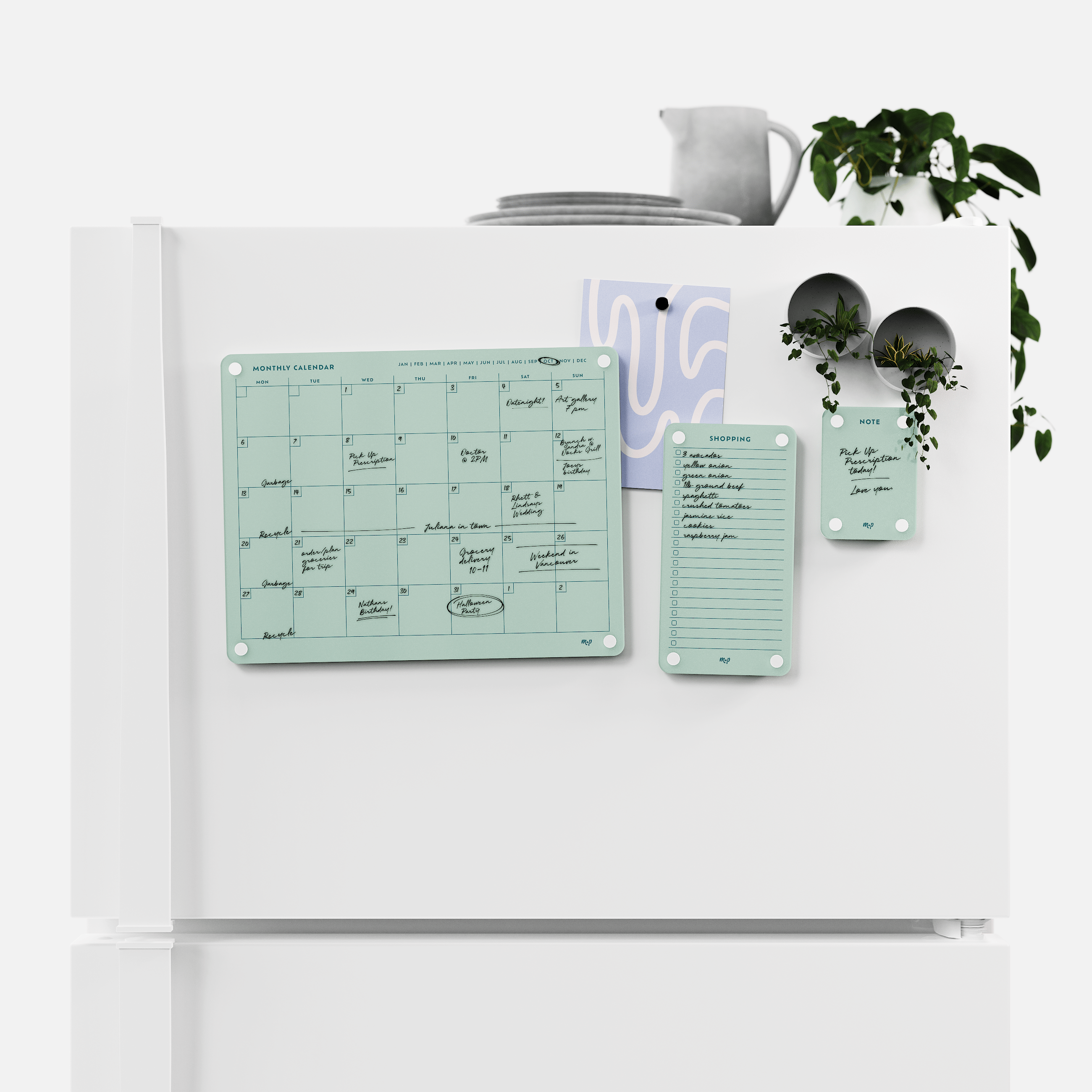 Seafoam green monthly calendar, shopping list and note board magnetised to a white fridge door